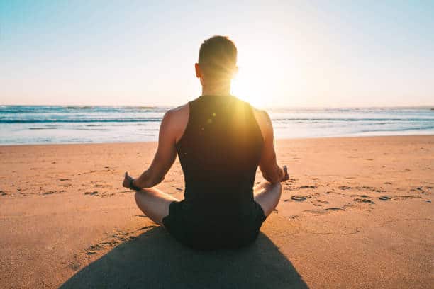 person meditating on the beach