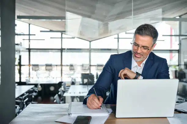 man researching on computer with notebook